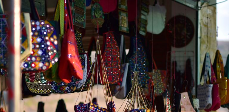 Puesto de feria con bolsas y artesanías coloridas colgando